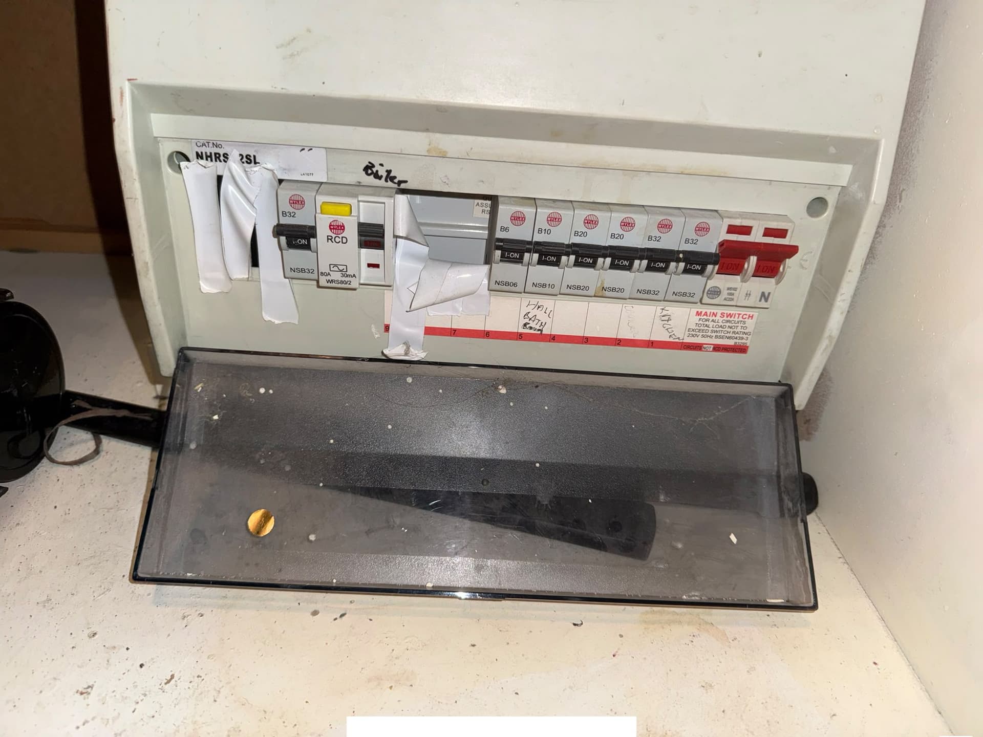 Consumer unit photographed during the inspection, with the cover open in front of the board.