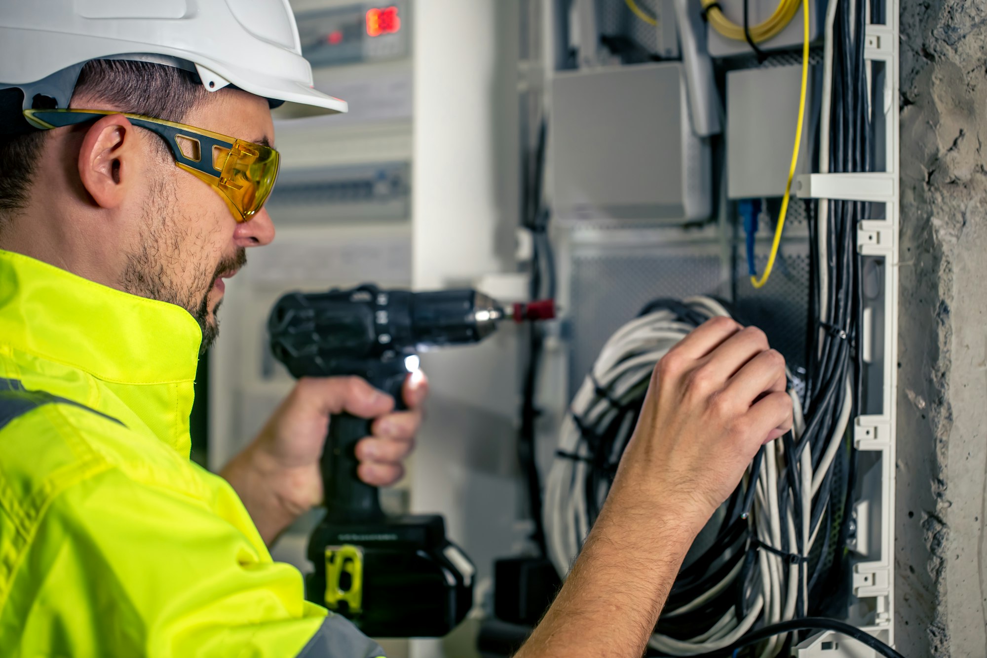 Man, an electrical technician working in a switchboard with fuses.