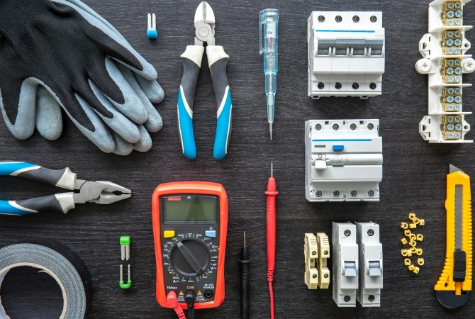 Different electrical tools on wooden background, flat lay.