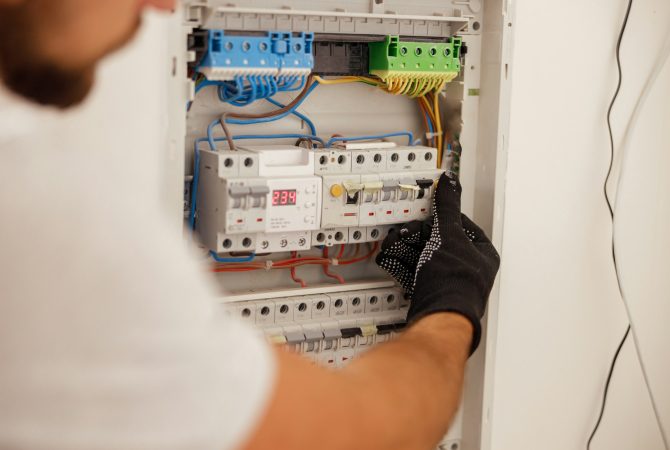 Hand of electrical technician working with fuses at the circuit breaker control cabinet on the