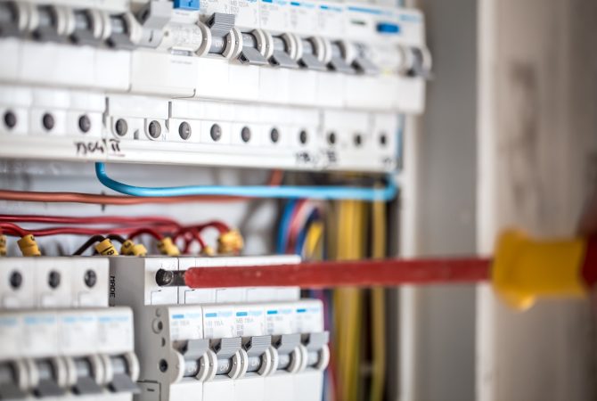 Man, an electrical technician working in a switchboard with fuses.