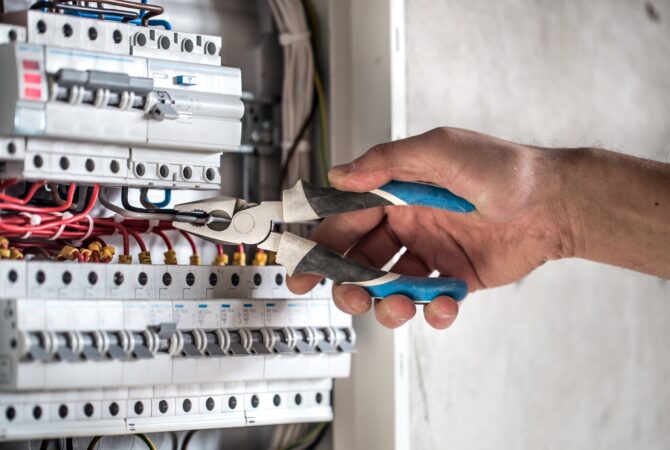 Man, an electrical technician working in a switchboard with fuses.