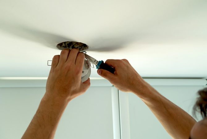 Man hands installing socket for light bulb. Repairs ceiling light indoor home in white room